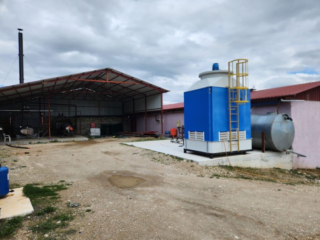 Outdoor rose oil distillation area with steam boiler system and raw material storage.